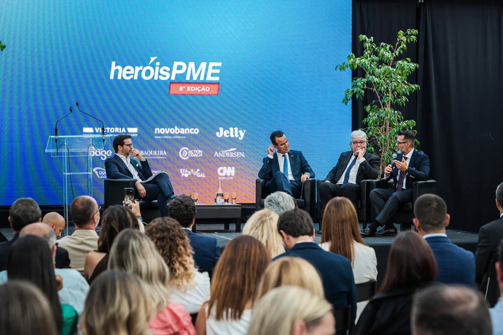 Painel de debate na 8.ª edição do evento Heróis PME, com quatro oradores em palco perante uma plateia